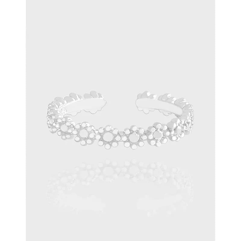 Open cuff ring in polished sterling silver with a line of small flower shapes along the band.
