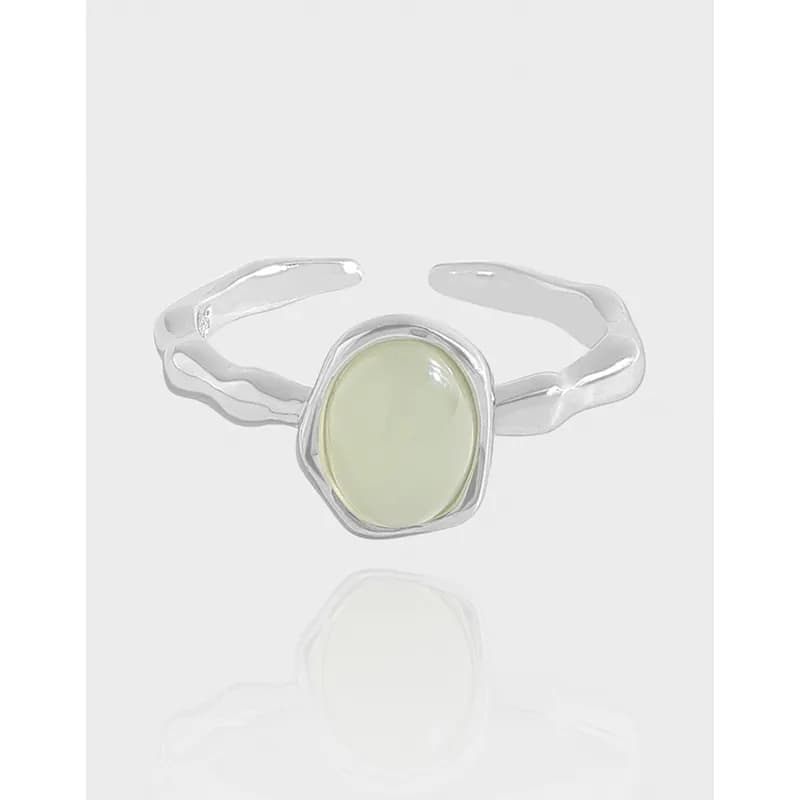 Silver ring with an oval pale green gemstone set in an irregular rounded bezel.
