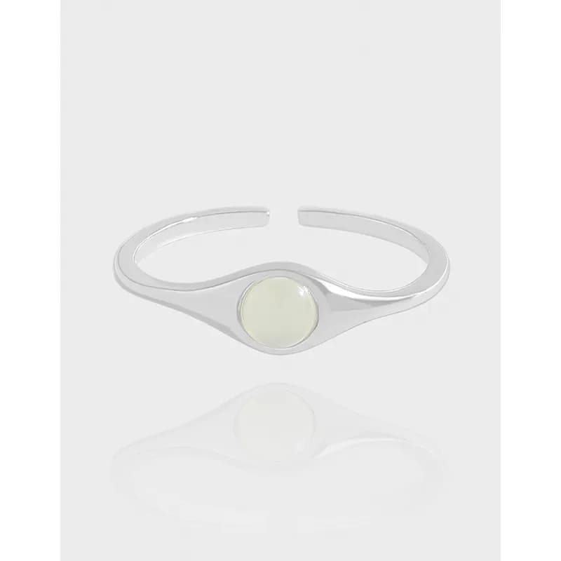 Polished sterling silver ring with an open sculpted band and a pale round cabochon bezel at the center.