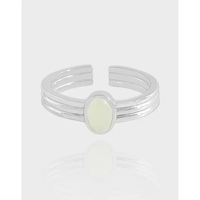 Polished sterling silver ring with a pale oval stone set in a bezel at the center, three-tiered split band design