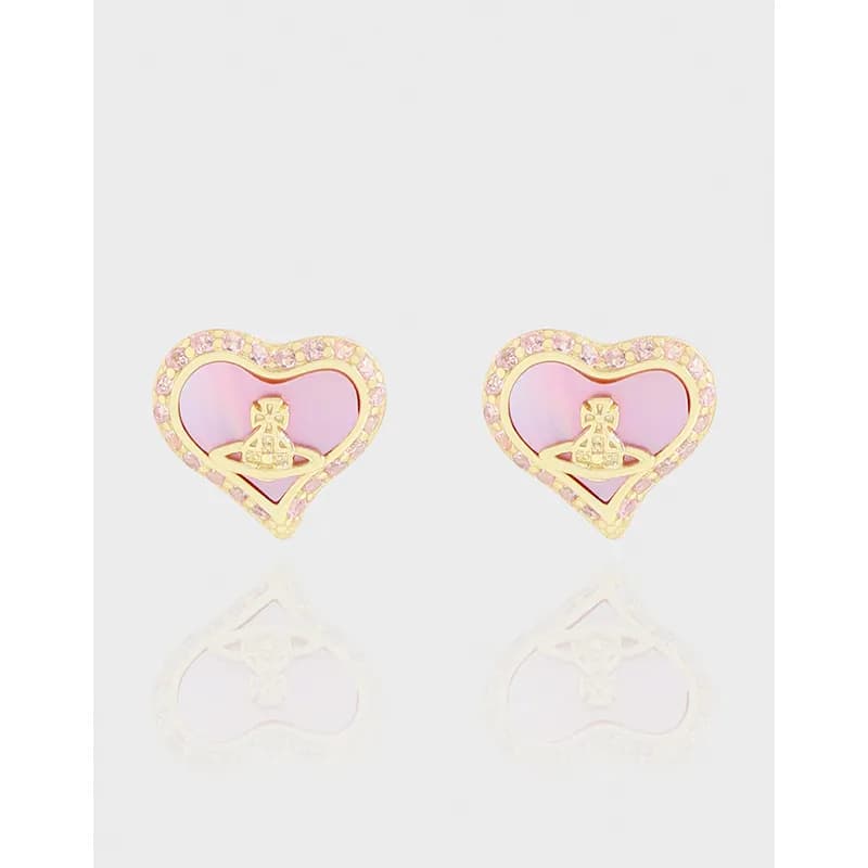 Two pink enamel heart earrings with crystal-bordered gold-tone edges and a small central emblem, set on a reflective surface.