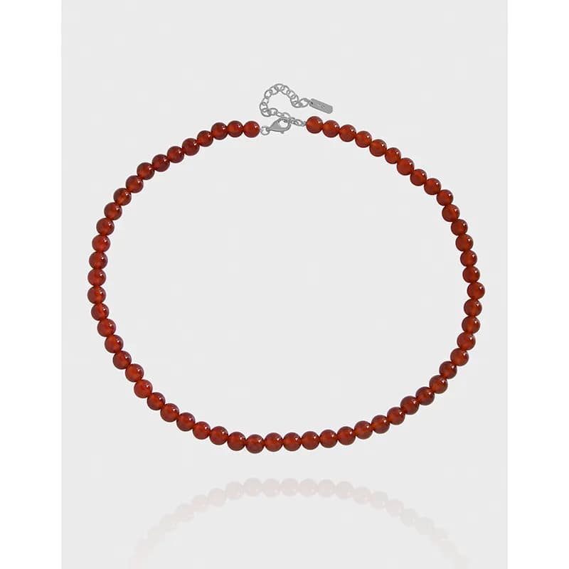 Polished red bead necklace in a circular layout against a white background.