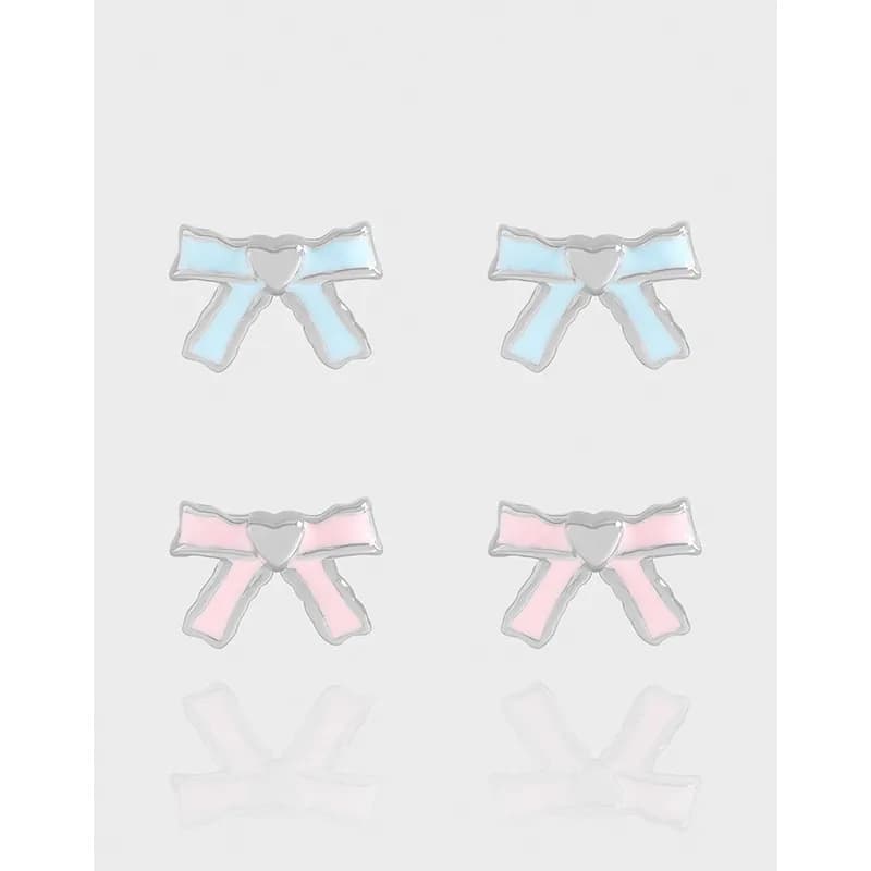 Pair of silver bow-shaped enamel stud earrings in pastel blue and pink on a light background.