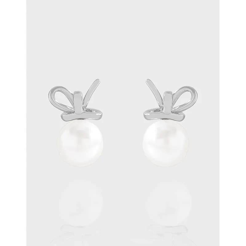 Polished sterling silver bow-topped pearl stud earrings displayed front-facing.