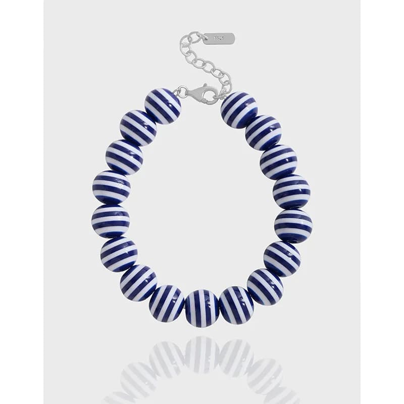 Sterling silver bracelet with evenly spaced blue and white striped beads and a lobster clasp.