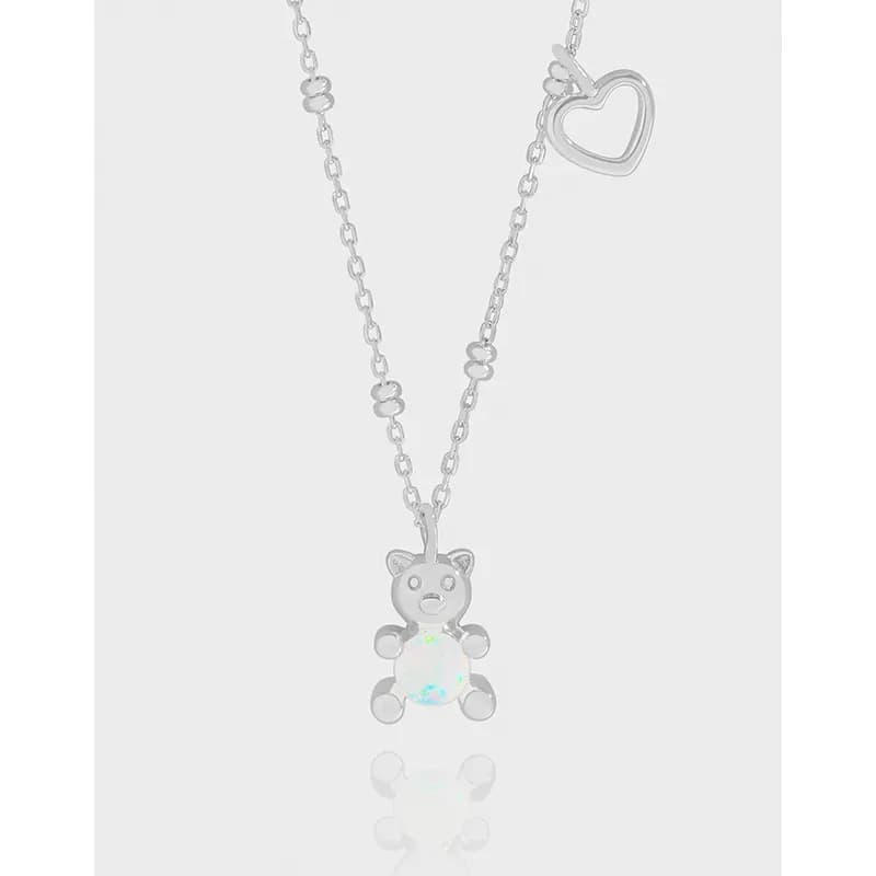 Polished sterling silver necklace with a bear pendant featuring an opal body and a heart charm on the chain.