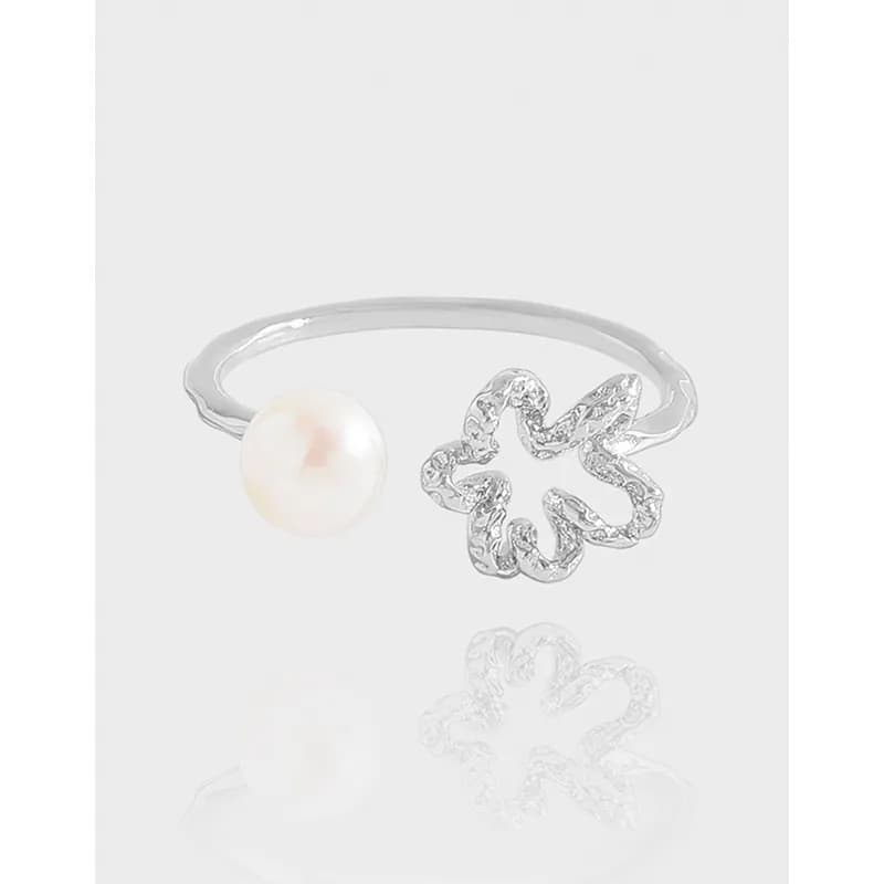 Open silver ring with a pearl on one end and a crystal-studded flower motif on the other.