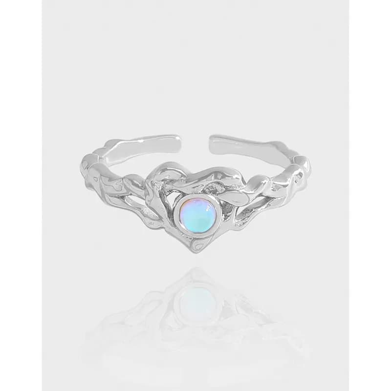 Polished sterling silver ring with a round opal cabochon set in a heart-shaped bezel at the center.