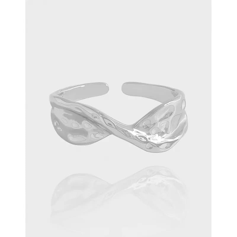 Polished sterling silver open-ring with a twisted crossing band on a light background.