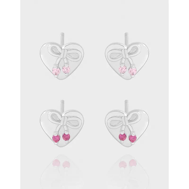 Pair of heart-shaped stud earrings in polished silver with a bow detail and pink drop stones.