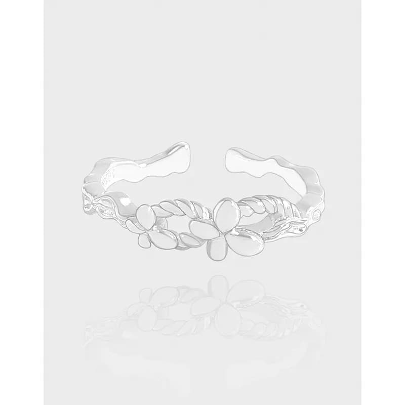 Polished sterling silver floral petal ring with braided band on a light background.