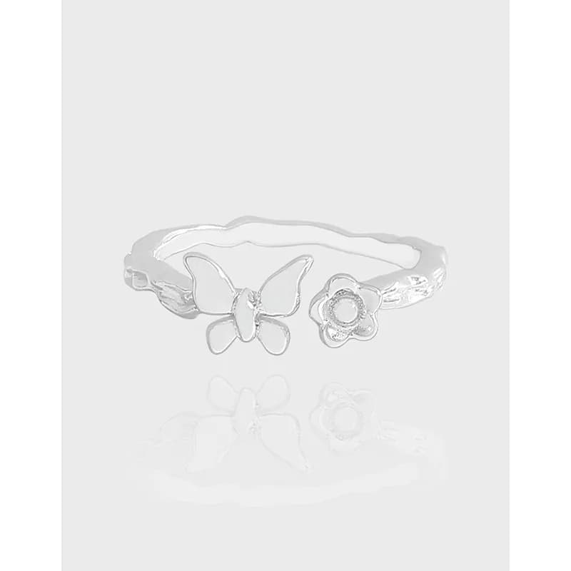 Polished sterling silver ring with butterfly and flower motifs on a pale background.