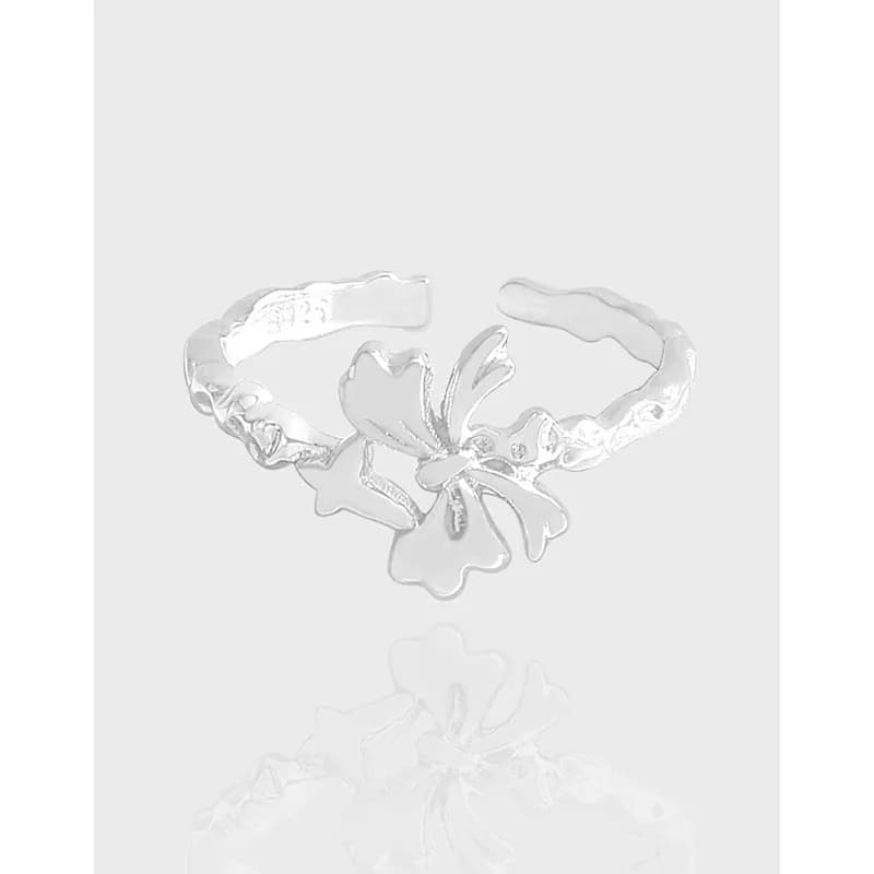 Open hammered silver ring with a sculpted flower and bow centerpiece