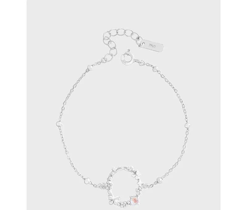 Polished sterling silver bracelet with a circular petal-ring centerpiece and delicate chain on a light background.