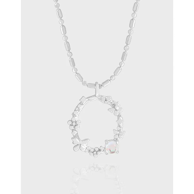 Sterling silver necklace with a floral circular pendant featuring tiny flowers and a pearl accent