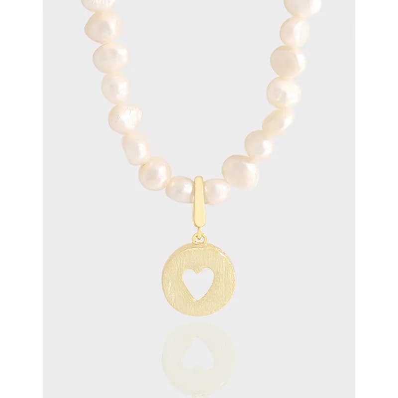Pearl bead necklace with a gold-tone heart-cutout disc pendant