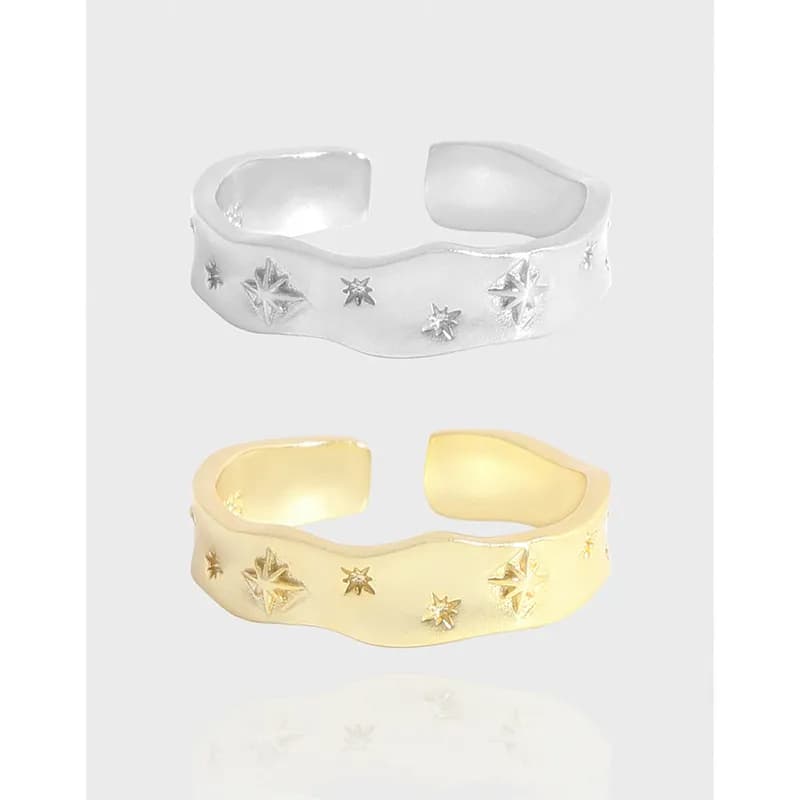 Polished sterling silver ring with a wavy band and starburst motifs.