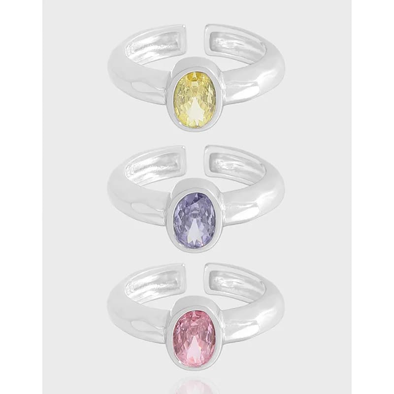 Three silver rings with bezel-set oval stones in yellow, lilac, and pink, shown vertically in a row.