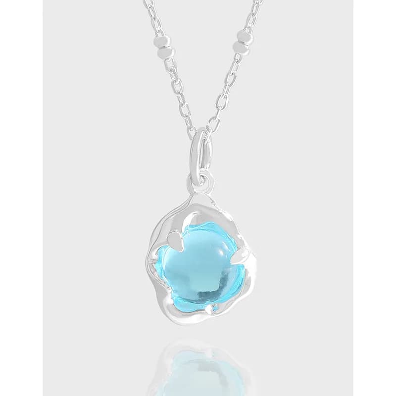 Polished sterling silver necklace with a floral bezel setting and light blue glass pendant