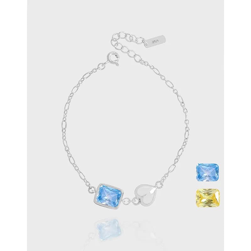 Delicate sterling silver bracelet with a square blue stone and a heart charm on a clean white background.