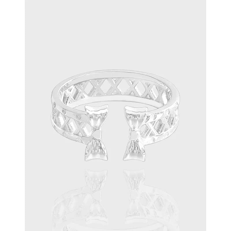 Polished sterling silver lattice ring with two front bow accents on a light background.