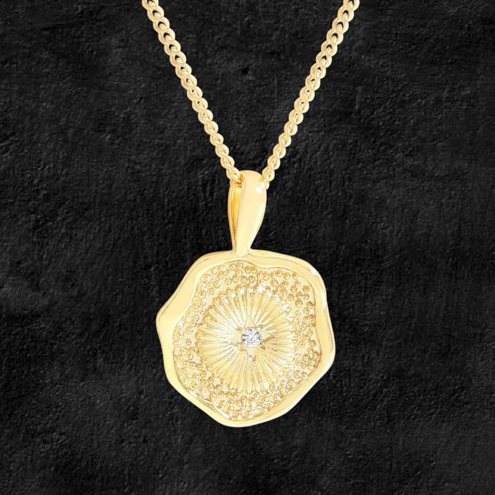 Gold-tone sunburst pendant with pave stones on a matching chain