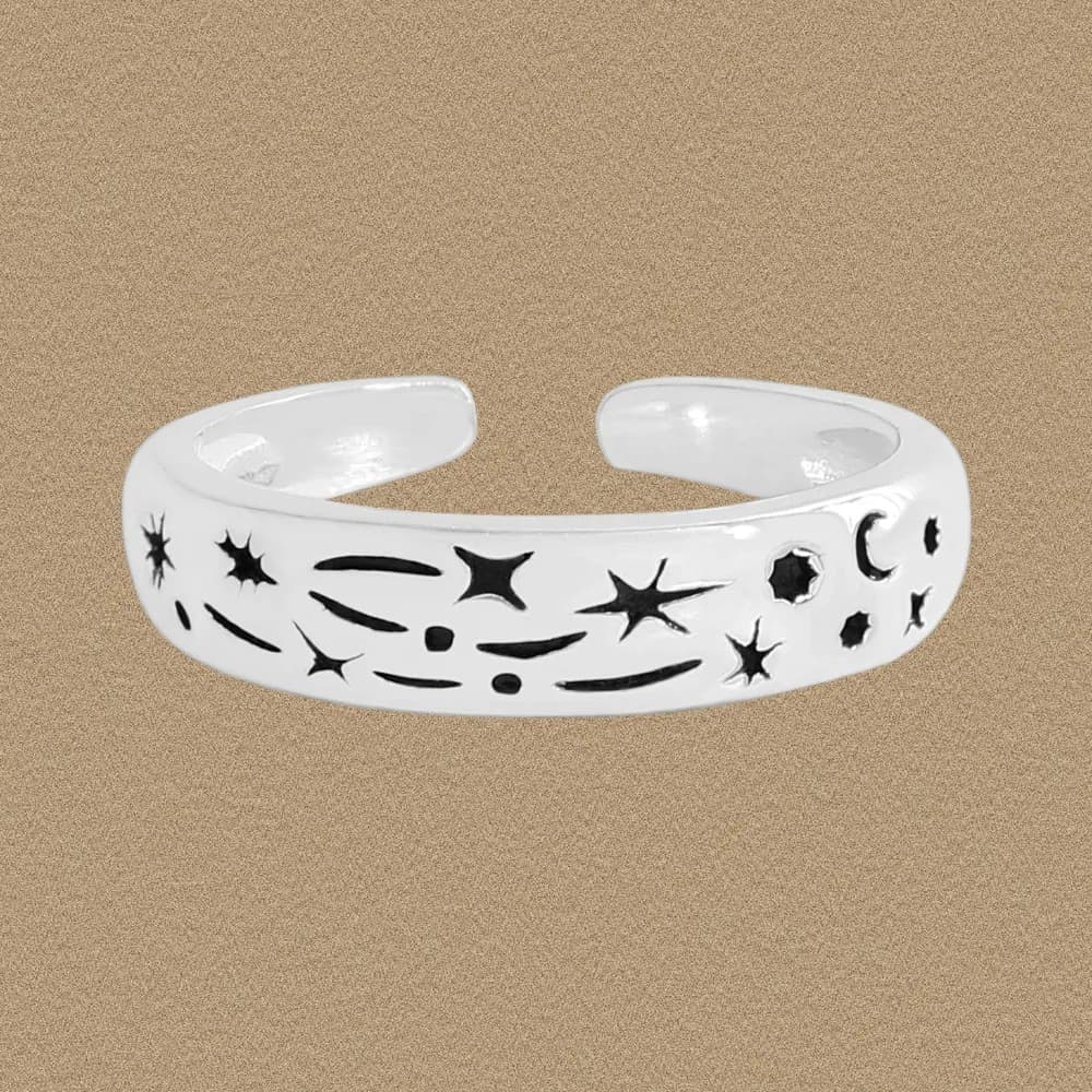 Open-ended sterling silver ring with star and moon engravings on a neutral background.