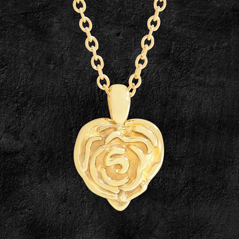 Gold-tone rose pendant on a polished chain against a black background.