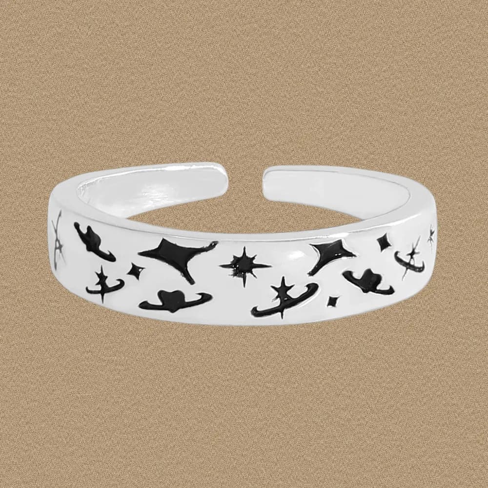 Wide silver ring with black star and abstract enamel motifs around the band.