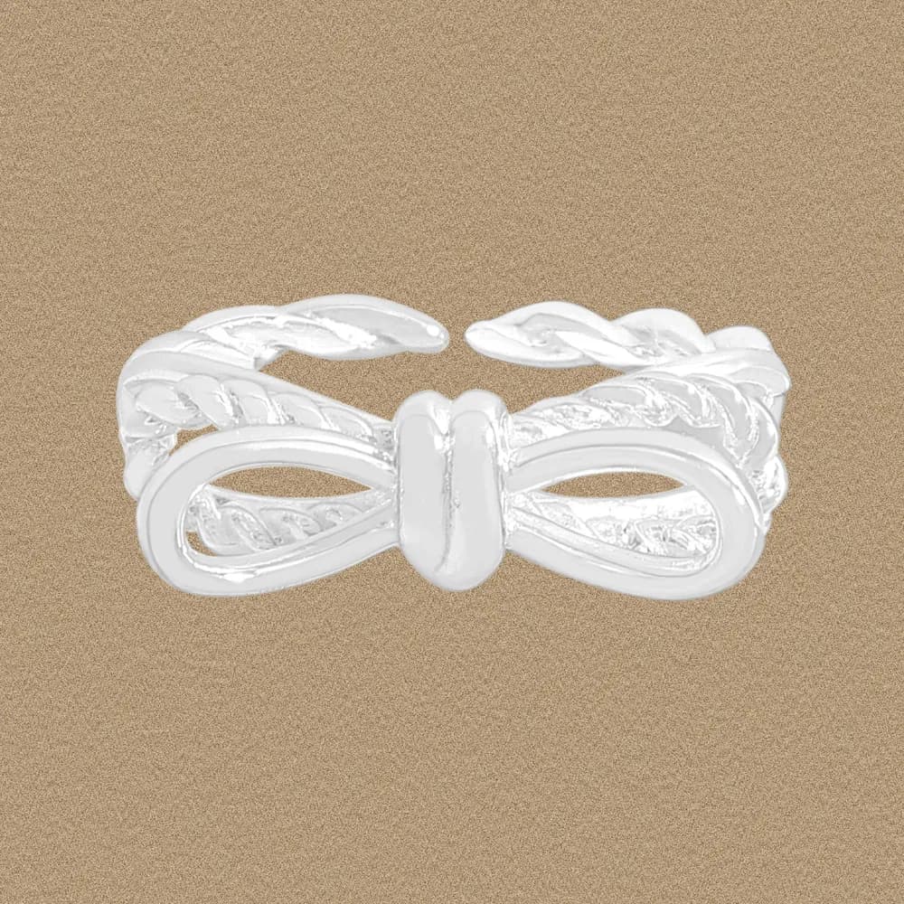Sterling silver bow knot ring with braided detailing on a warm brown background.