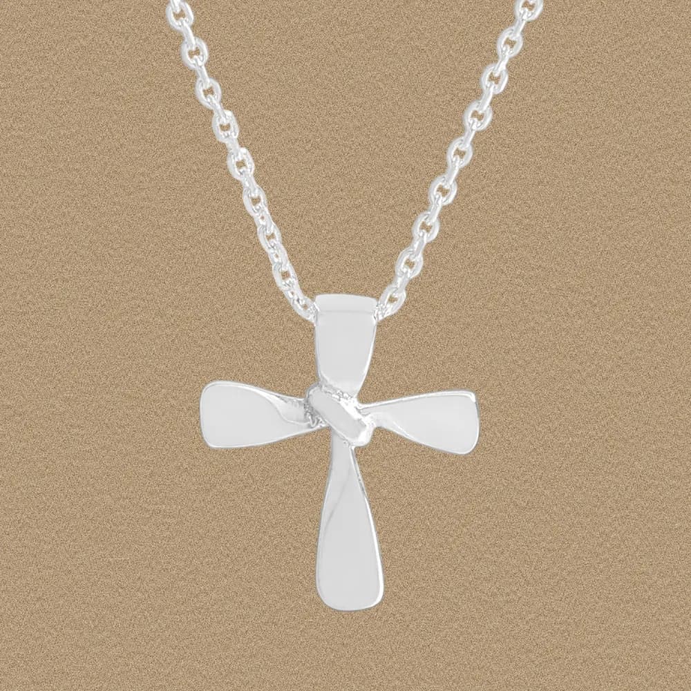 Polished sterling silver cross pendant on a delicate chain against a neutral background.