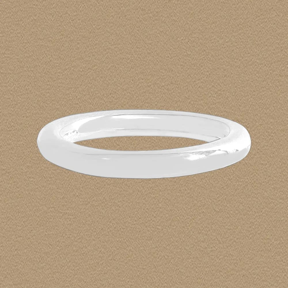 Polished sterling silver band ring photographed on a warm textured background.