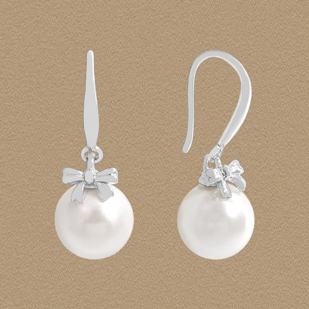Polished sterling silver pearl drop earrings with a small bow motif and hook backs.