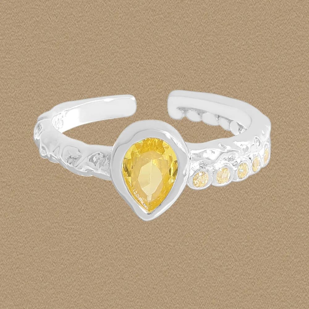 Polished sterling silver ring with a pear-cut yellow gemstone centerpiece and decorative side-stones
