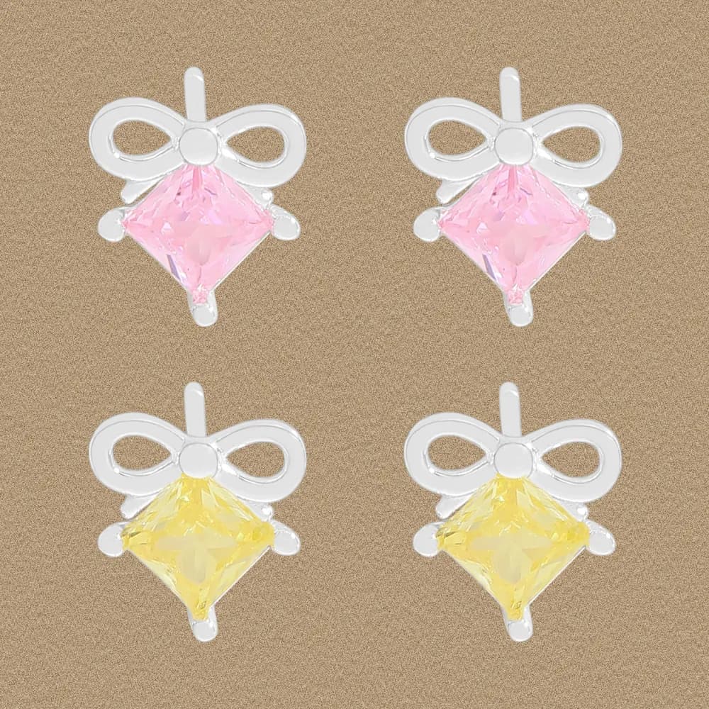 Four silver bow stud earrings with pink and yellow square-cut crystals on a beige background.