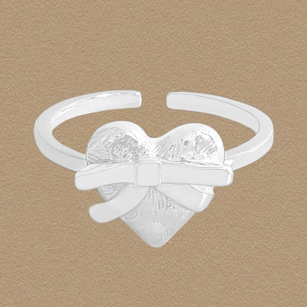 Polished sterling silver Heart Bow Ring with an open adjustable band on a neutral background.