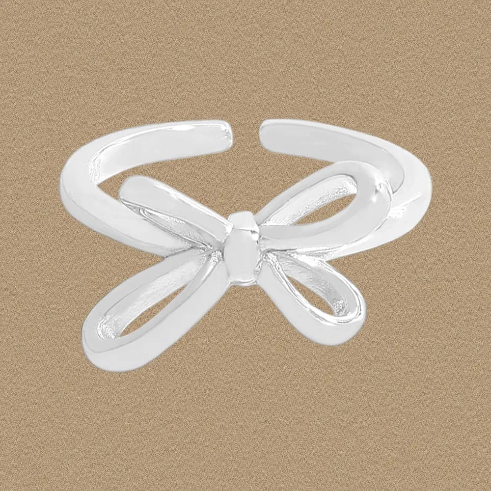 Polished sterling silver Bow Ring with a delicate ribbon motif on an neutral background.