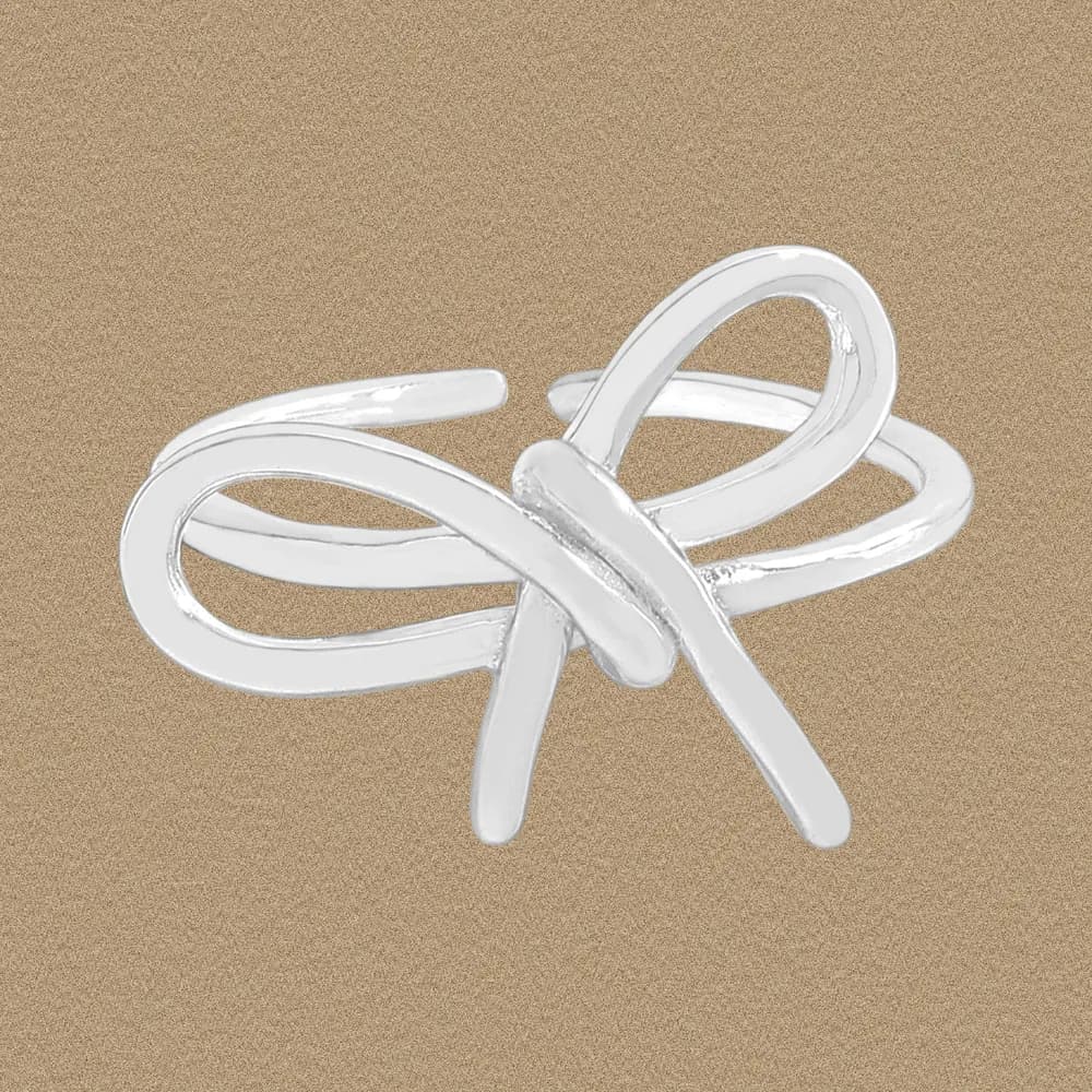Polished sterling silver intertwined knot ring resting on a sandy background.