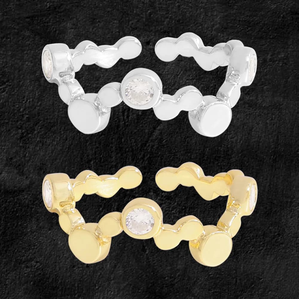 Polished silver and gold-tone ring with a wavy line of connected discs and a central bezel-set stone.
