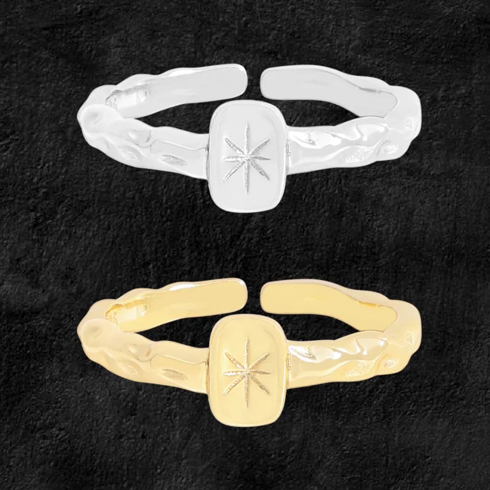 A polished ring with a rectangular bezel featuring a starburst engraving on an organic, textured band.