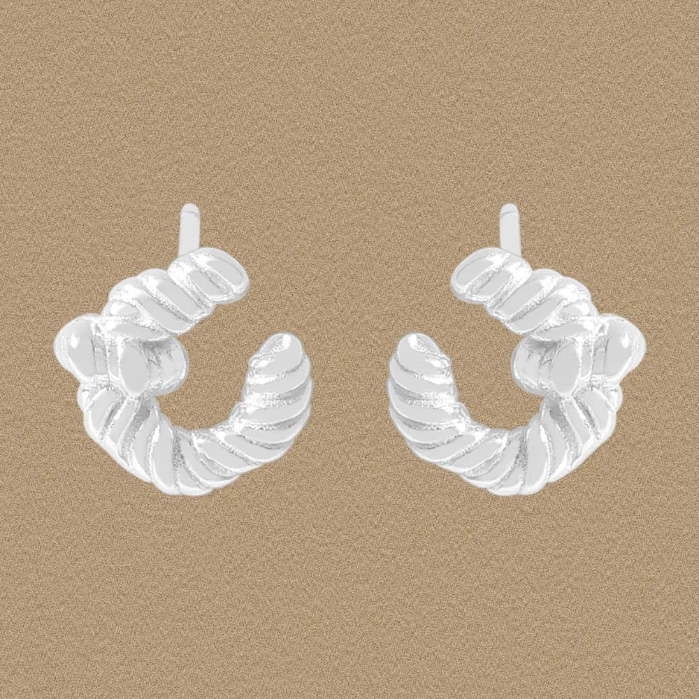 A pair of polished sterling silver twisted rope hoop earrings on a tan background.
