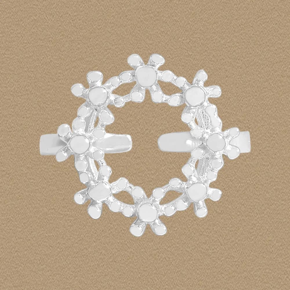 Polished sterling silver ring with a circular floral halo design on a beige background.