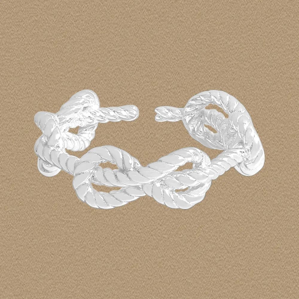 Open-ended sterling silver rope knot ring on a sandy background
