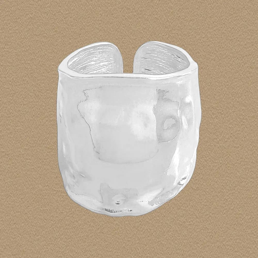 Close-up of a wide, irregular hammered sterling silver ring with an open back.