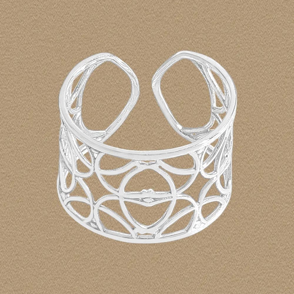 Wide sterling silver ring with circular openwork filigree on a warm background