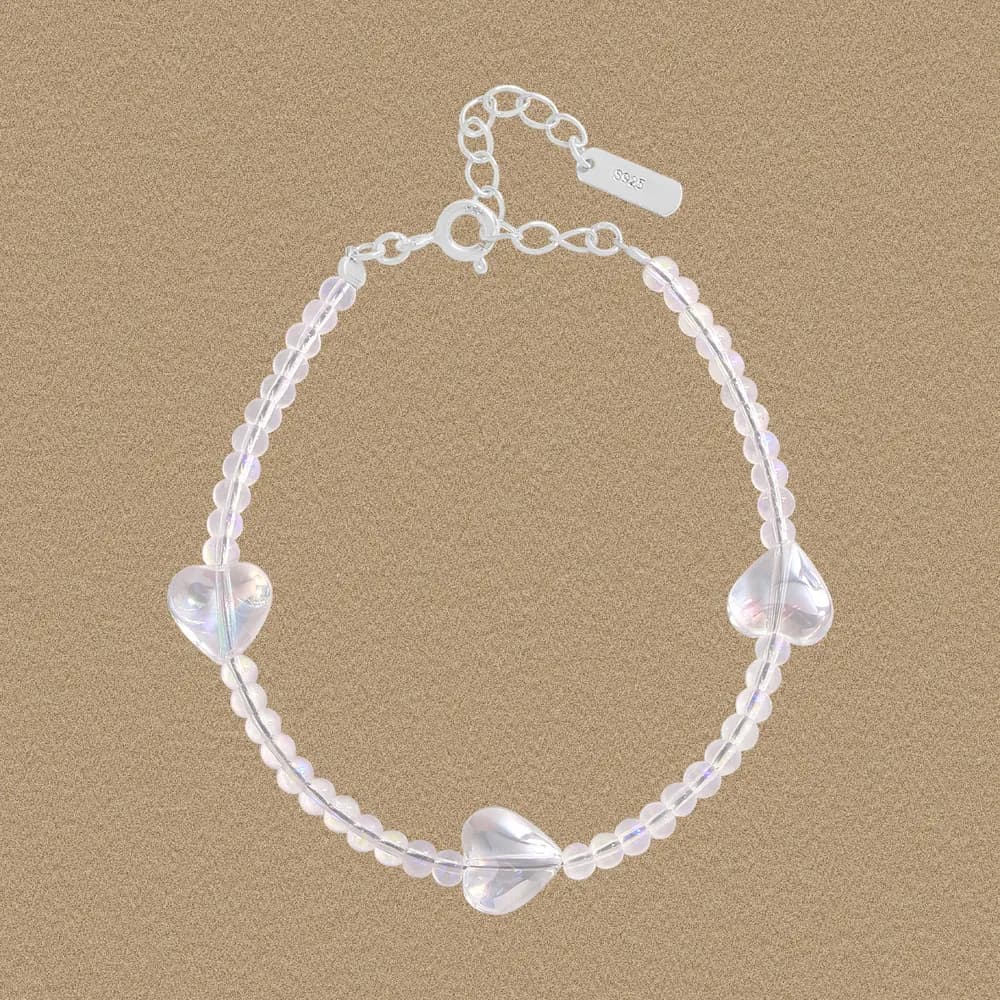Polished sterling silver bracelet with clear iridescent beads and three heart-shaped accents on an adjustable chain.