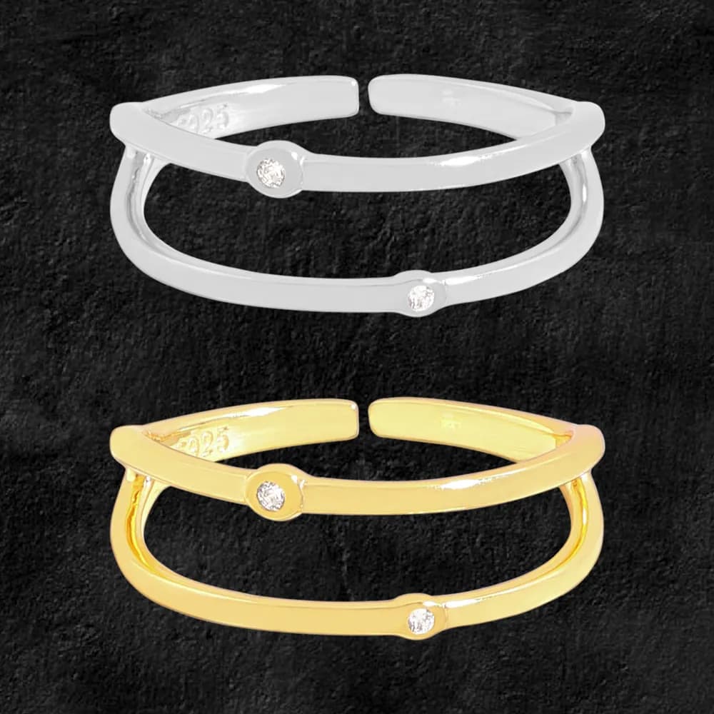 Polished double-band ring in silver and gold tones, each with a small bezel diamond at the center, shown against a dark background.