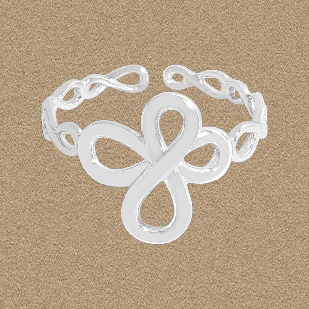 Polished sterling silver ring with a large infinity-loop centerpiece against a warm beige background.