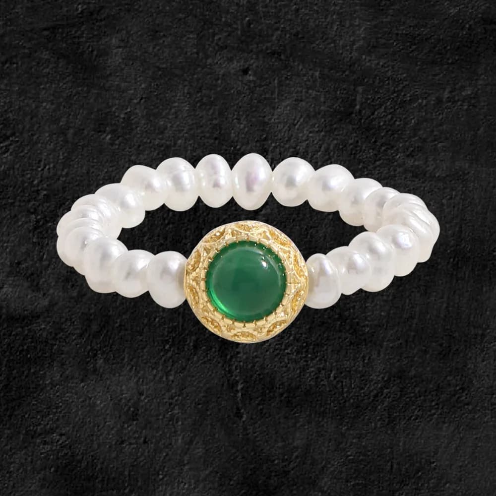 Pearl bead ring with a green cabochon centerpiece set in a textured gold bezel on a polished silver band.