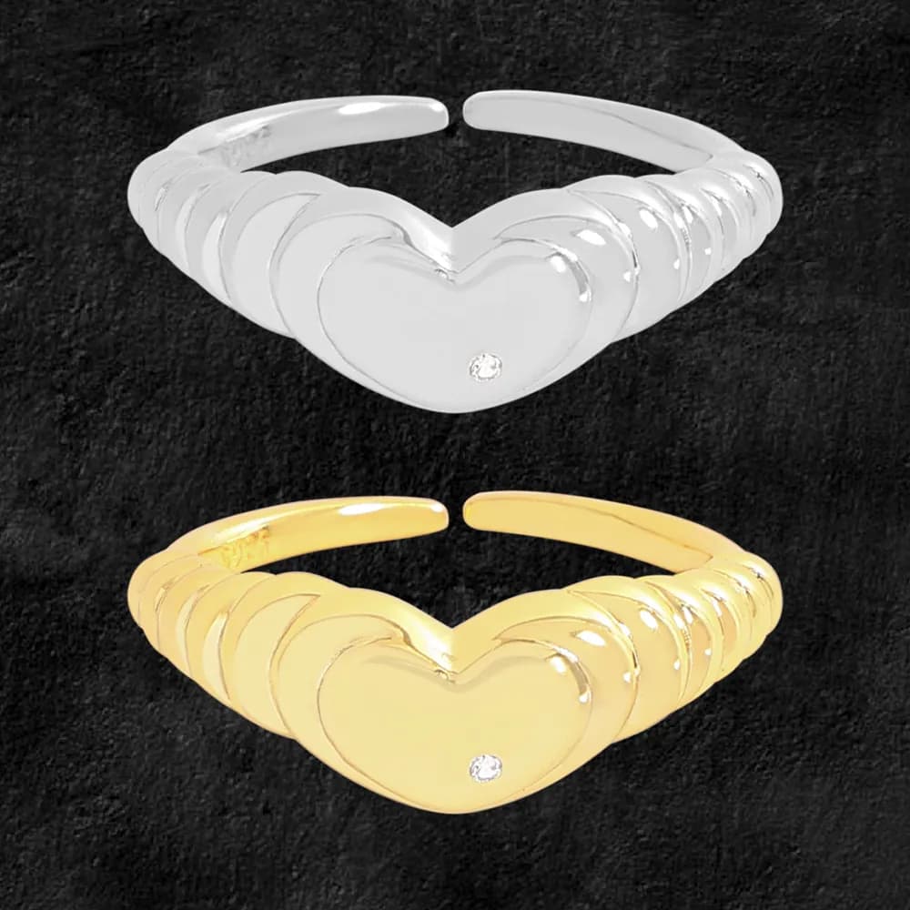 Polished sterling silver ring with stacked heart motifs and a small gemstone on the central heart, shown in a silver and gold pair.